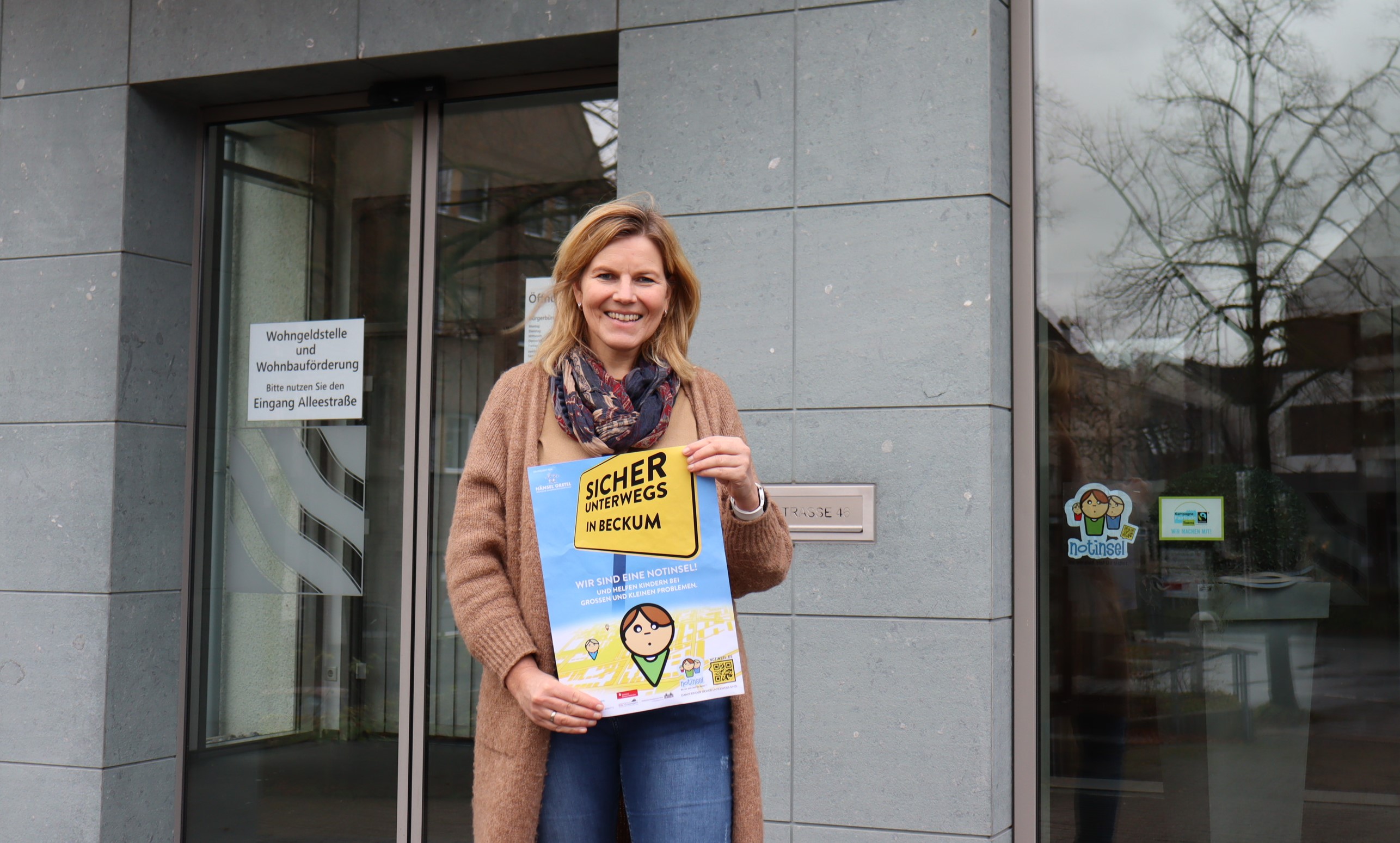 Silke Knipping holds up the poster in front of the town hall entrance
