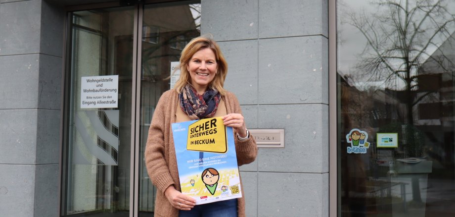 Silke Knipping holds up the poster in front of the town hall entrance