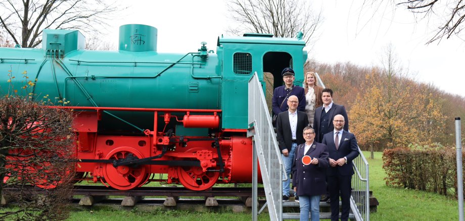 The decommissioned locomotive in the Phoenix activity park arouses anticipation for the planned shuttle service: bottom row (from left) Gudrun Rassat (Osnabrücker Förderkreis Eisenbahn-Tradition) and Mayor Michael Gerdhenrich, centre: Uwe Denkert (City of Beckum) and Dr Daniel Dierich (Energieversorgung Beckum), top row: Burkhard Rassat (Osnabrücker Förderkreis Eisenbahn-Tradition) and Marianne Witt-Stuhr (City of Beckum).