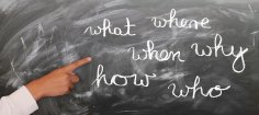 Blackboard with chalk written questions What, Where, when, how and who
