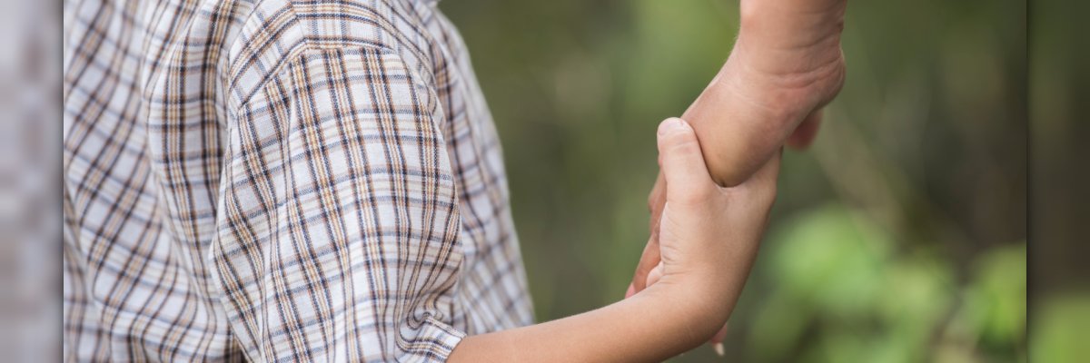 Kind houdt de hand van een volwassene vast