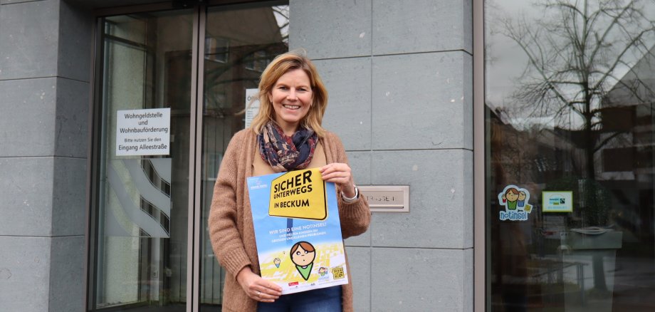 Silke Knipping hält das Plakat vor dem Rathauseingang hoch