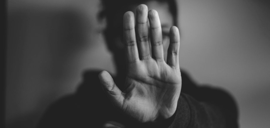 Frau hebt ihre Hand und sagt so Stopp