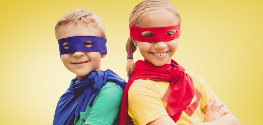 Portrait of kids in superhero costumes against yellow background